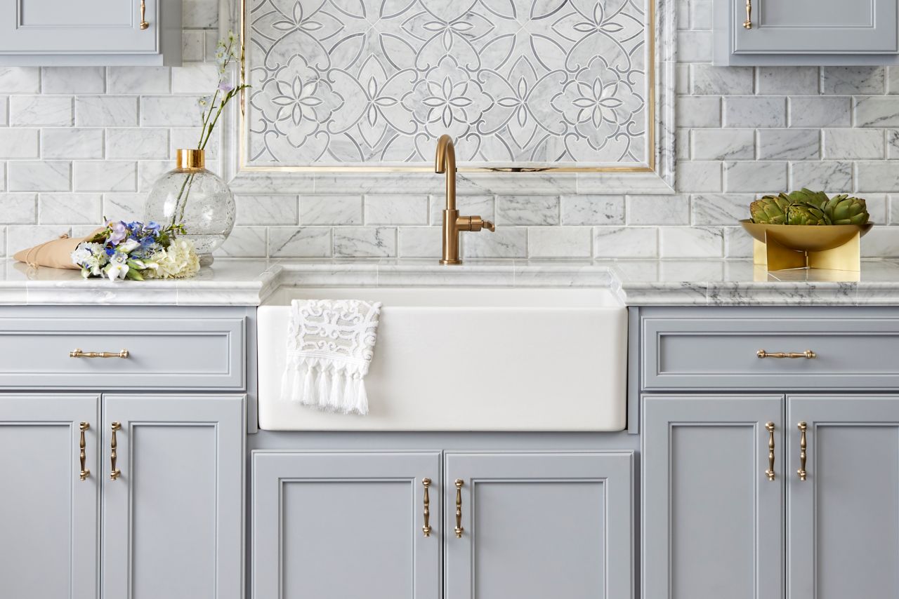 Kitchen with porcelain tile on floor resembling wood planks. Marble counter tops set under a backsplash of marble subway tile accented with mother of pearl and marble mosaic deco framed with marble and gold profiles.