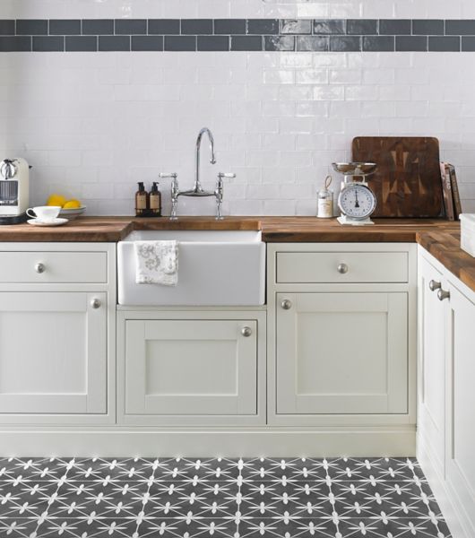 Kitchen area with white subway tile and a blue  border also in this collection.  The floor is a patterned ceramic in charcoal and white.