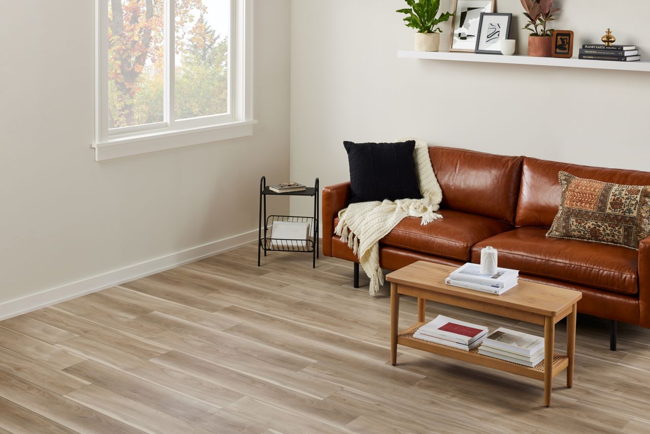 Living room with light brown luxury vinyl flooring and brown leather sofa.