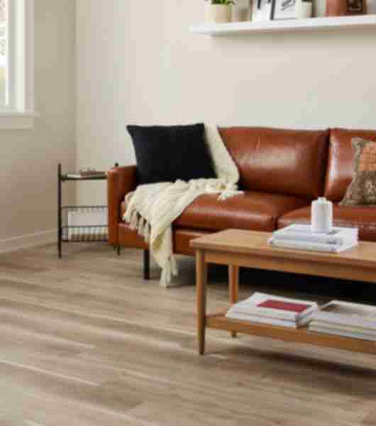 Wood-look luxury vinyl flooring with a brown leather couch and wood coffee table.