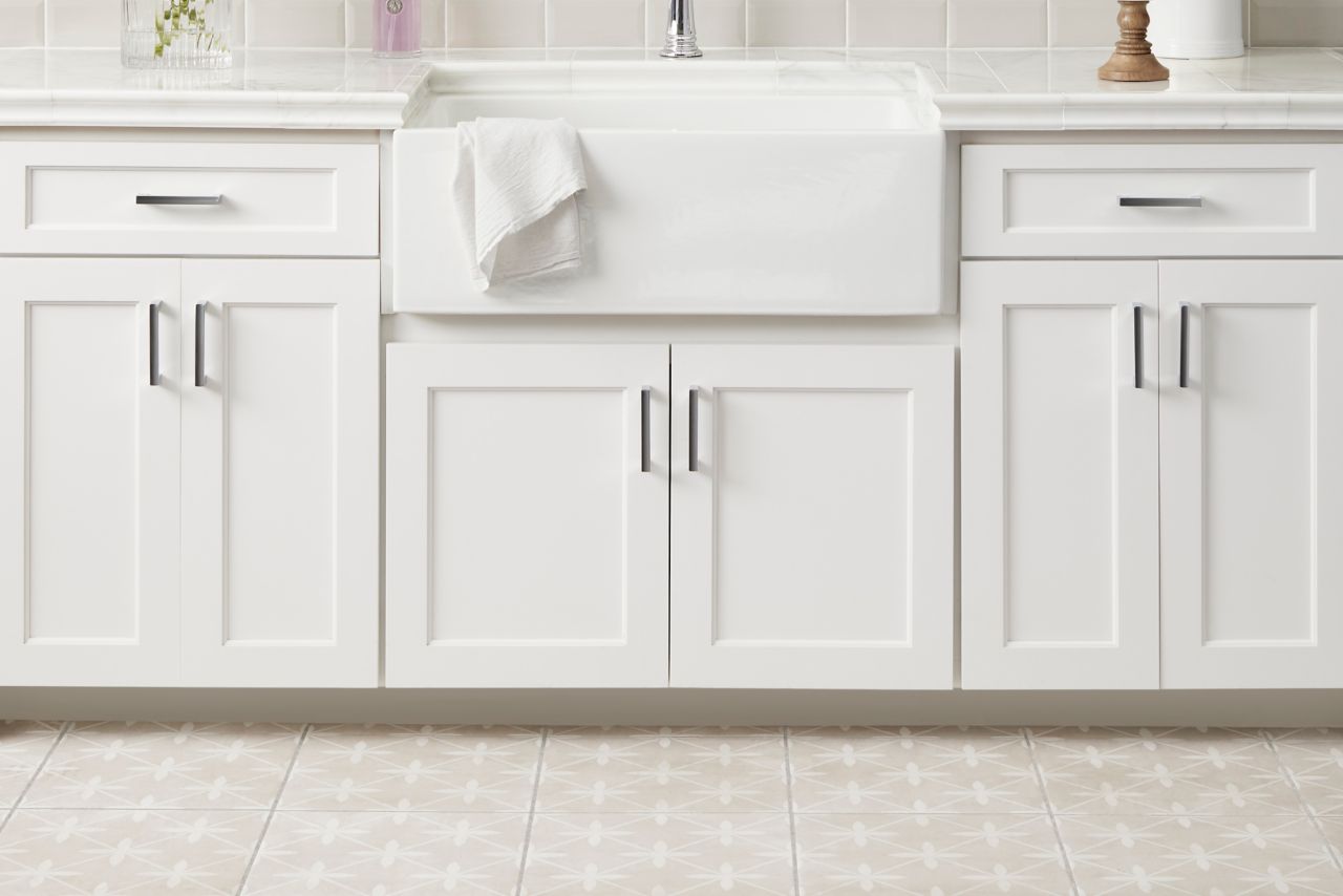 Kitchen with porcelain tile on floor in a geometric pattern.  Marble counter tops set under a ceramic subway tile accent with glass deco framed above the sink.