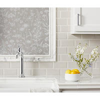 Thumbnail image of Close up image of kitchen with tiled counter and backsplash. Profiles on counter edge and deco frame are natural marble in grey, black and white. Deco is a large profile glass tile in a soft floral pattern. Stone profiles lend to subway field tile with beveled edge.