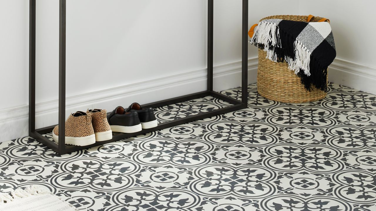 A console table with a marble top and black metal base stands on a black and white patterned tile floor in a modern entryway.