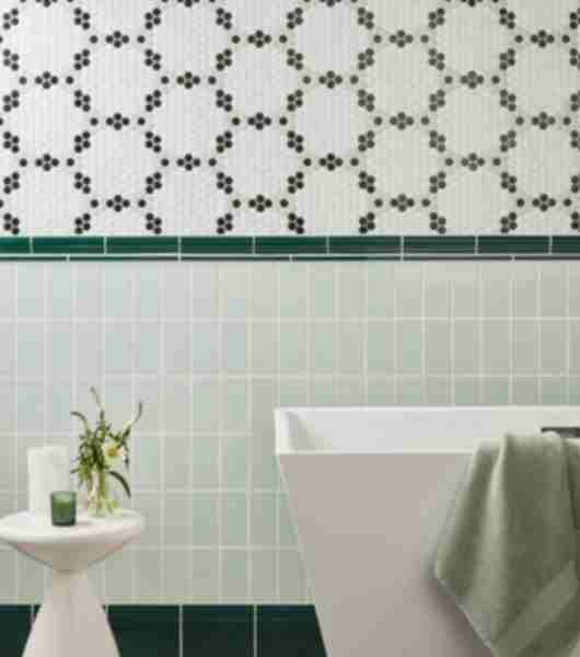 Bathroom wall with half black and white mosaic and half pale green with dark green trim.