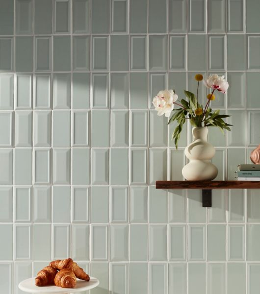 A backsplash combines three varieties of 3x6-inch, glossy mint green Imperial ceramic subway tile (flat, beveled and framed) in a vertical straight-stack pattern.