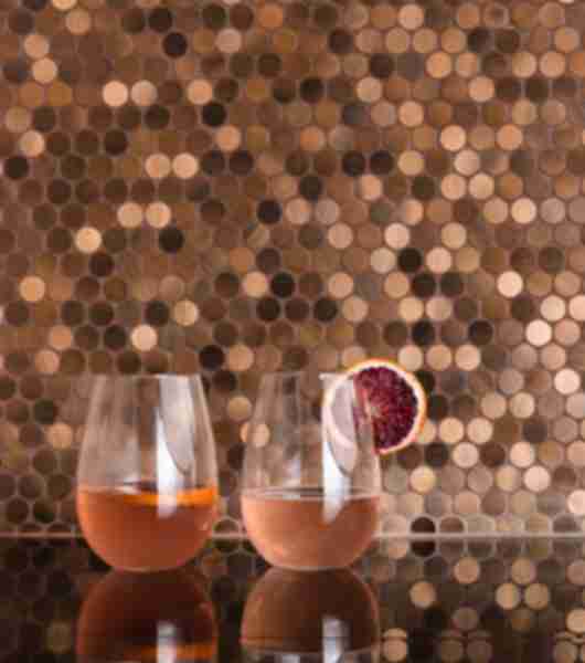 Copper penny round mosaic wall tiles add a brushed metal look to the backsplash of this dining room bar area.