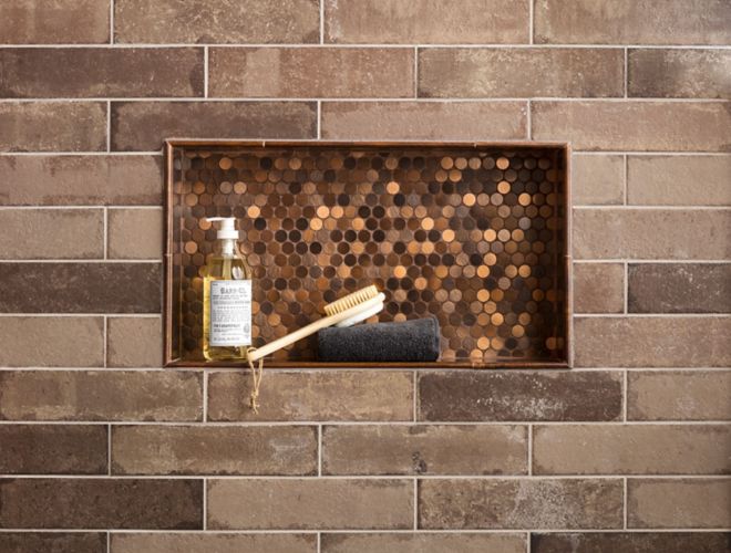 Brick subway wall tile in shower with copper penny round in recessed shelf.