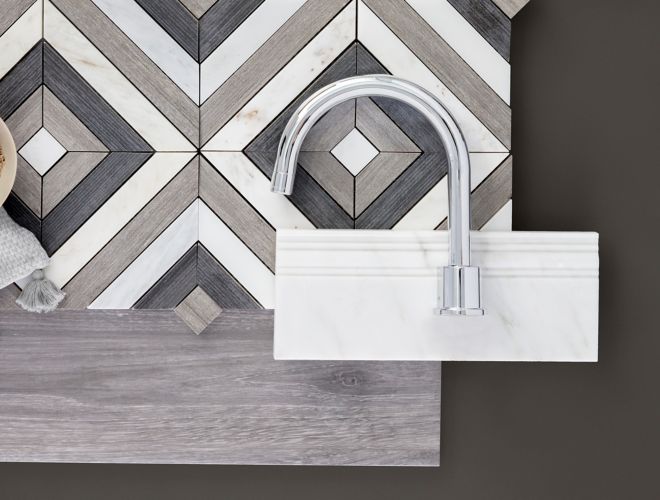 Mixed material brown and grey tiles, white marble skirting, and chrome faucet on dark grey table.