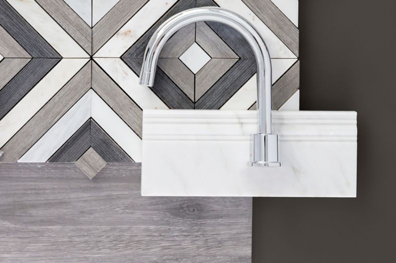 Mixed material brown and grey tiles, white marble skirting, and chrome faucet on dark grey table.