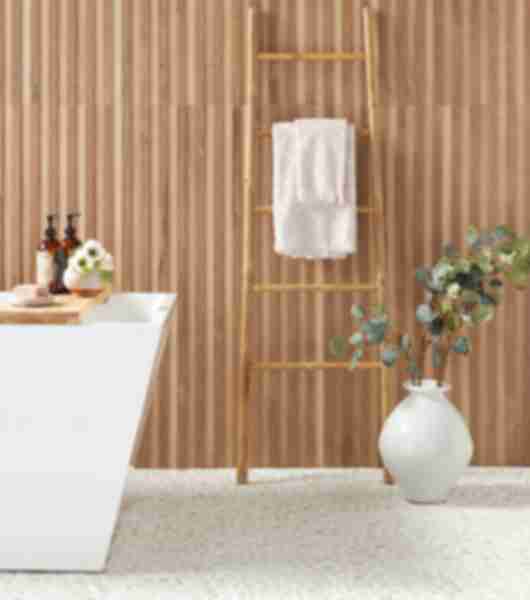 Bathroom area with a wood look tile with raised panels ran vertically.   Room has a soaking tub and potted plant.