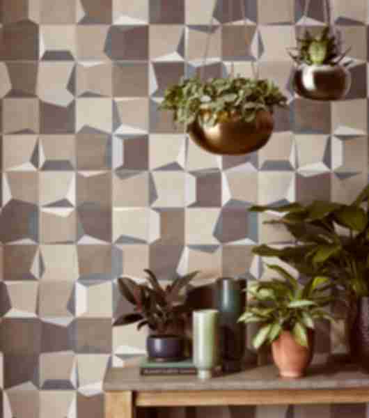 Side table with plants and hanging plants above all sit in front of thus ceramic tile feature wall in a 3d print of geometric shapes.