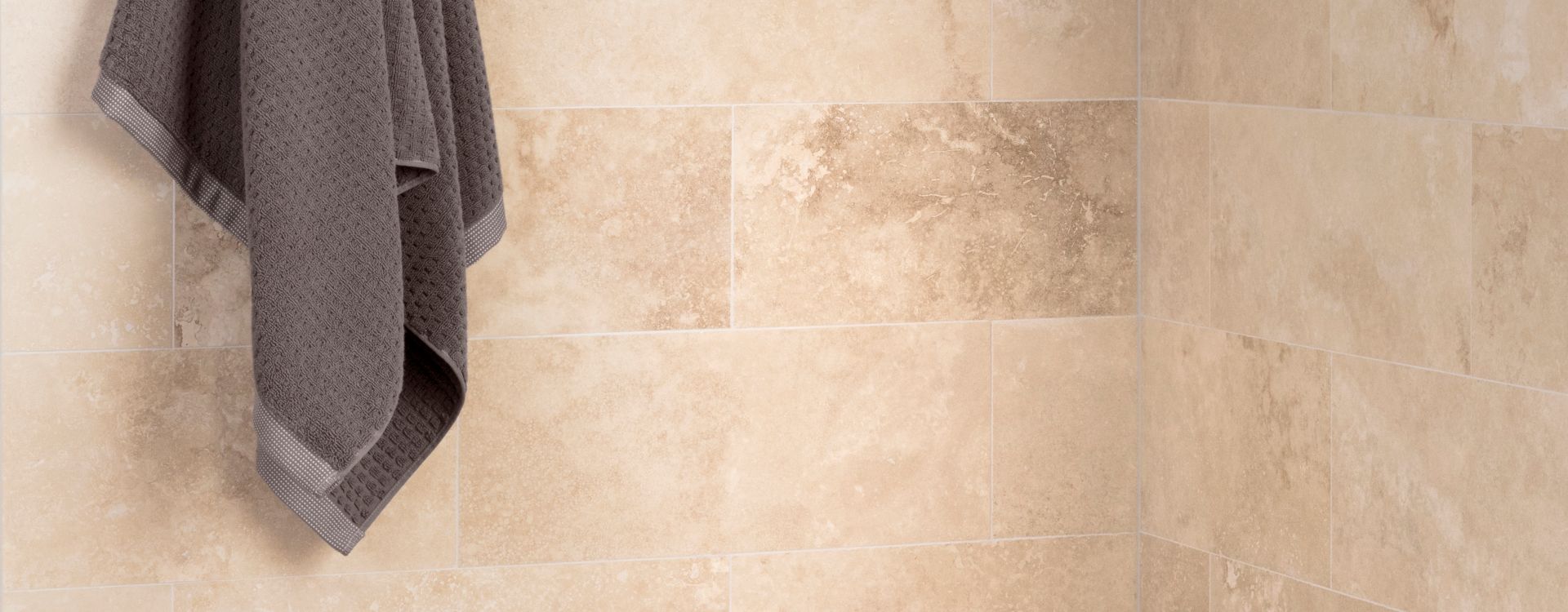 Corner of shower with shelf, brown stone wall tile, and brown and ivory glass mosaic.