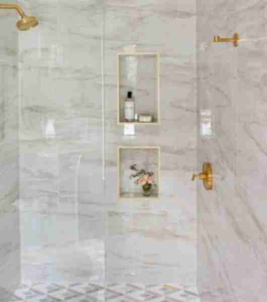 Shower with marble tile, gold fixtures and two small niches