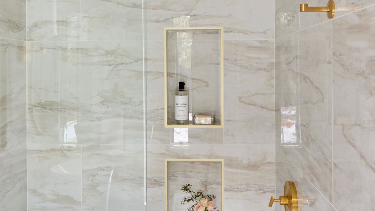 Shower with marble tile, gold fixtures and two small niches