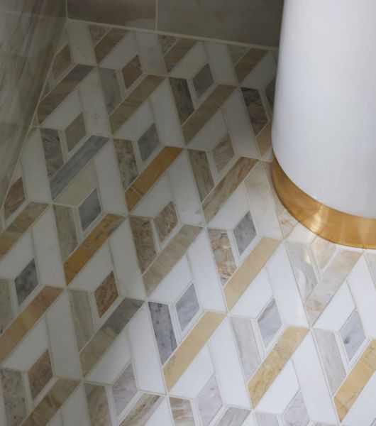 Corner shot of a shower with gold, white and grey diamond-shaped mosaic tile floor.