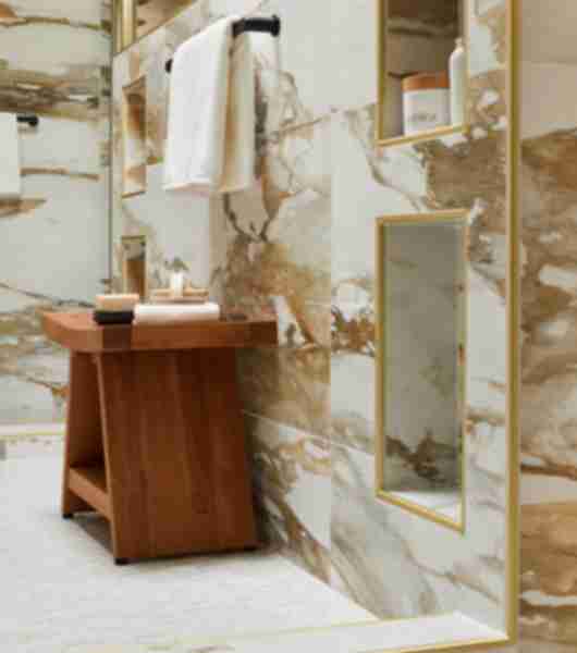 Shower with marble-look tile with bold gold and ochre veining.