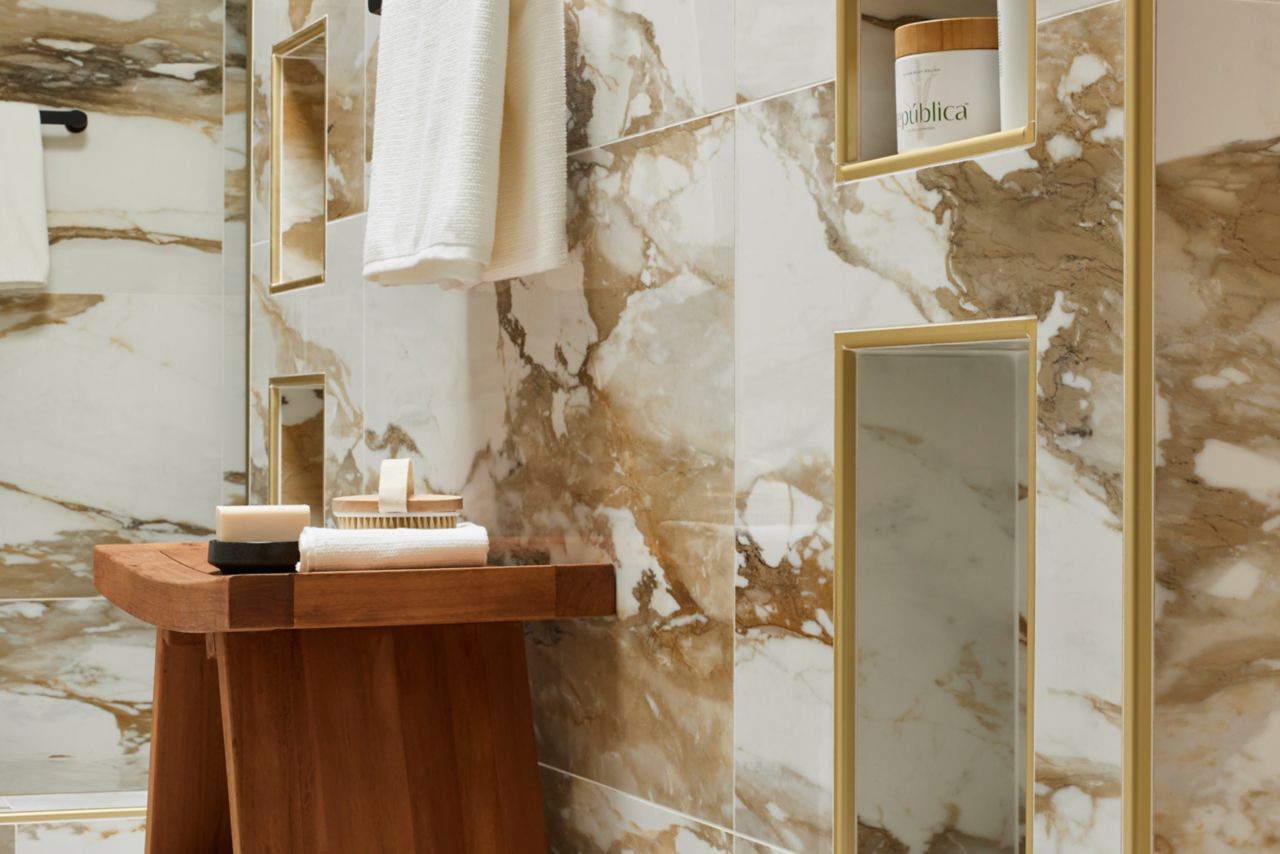 Shower with marble-look tile with bold gold and ochre veining.