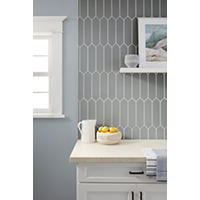 Thumbnail image of Kitchen backsplash using cool greige toned tile in a picket shape ran vertically.  Countertops are light beige and cabinets are white with black hardware.