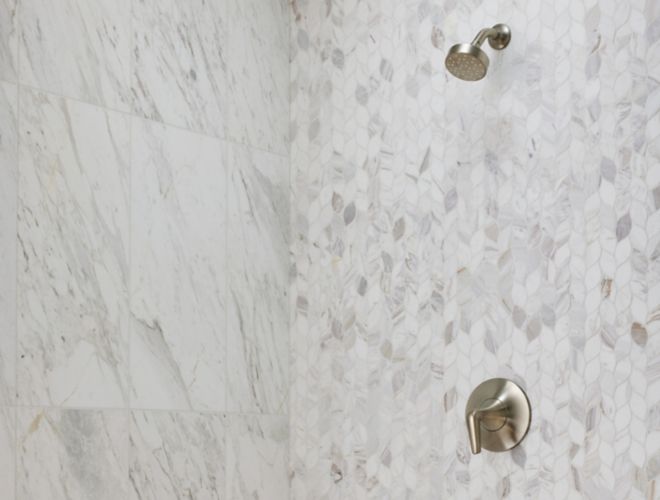 This elegant shower features leaf-shaped marble and large-format marble tile walls.