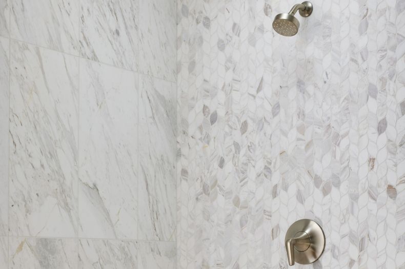 This elegant shower features leaf-shaped marble and large-format marble tile walls.