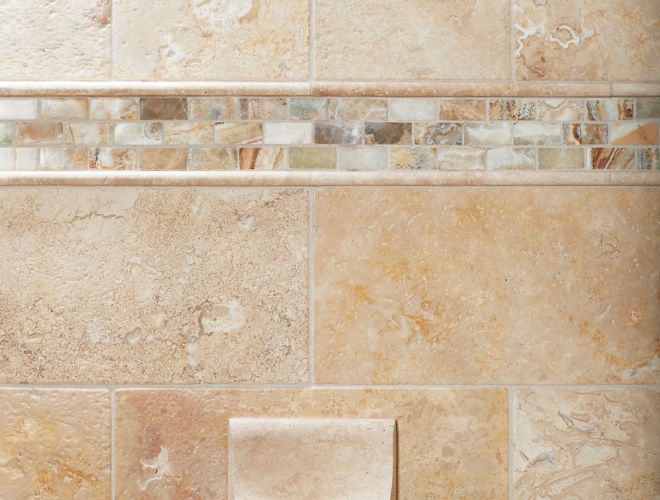 Shower wall with beige tile, mosaic accent, and soap dish.