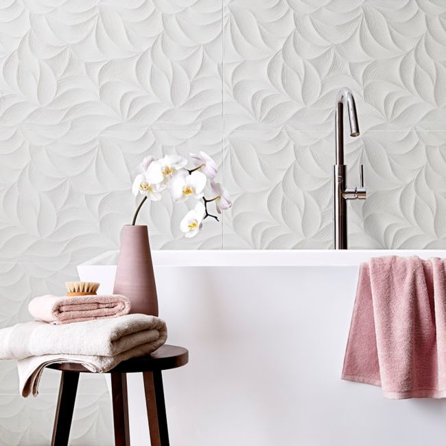 Large freestanding tub with a white textured tile wall behind it and pink accents.