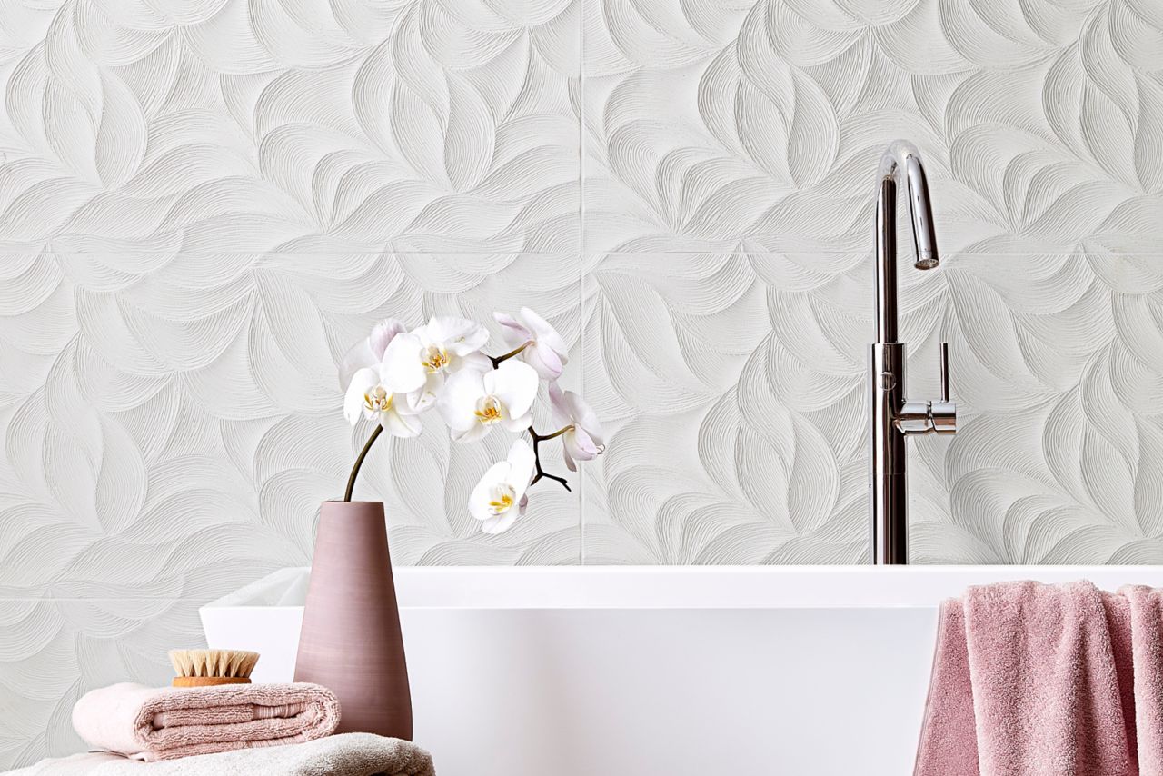 Large freestanding tub with a white textured tile wall behind it and pink accents.