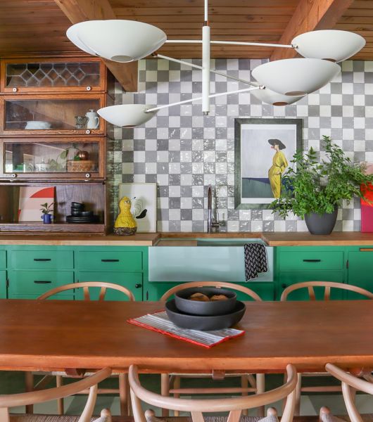 Table and chairs in front of green kitchen counters and white and grey tiled wall