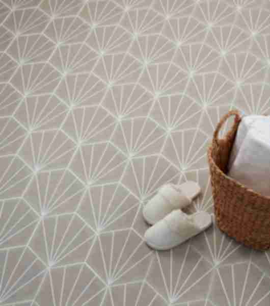 Taupe hexagon tile on floor with towel in whicker basket and slippers.