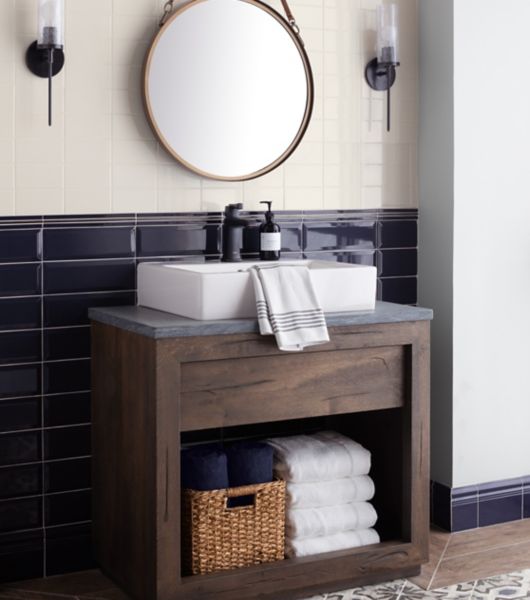 Bathroom with blue and ivory colored ceramic tile on wall matching base and a patterned and wood look tile on floor.