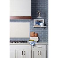 Thumbnail image of Marble counter top with blue ceramic tile backsplash with framed accent tile above range top.
