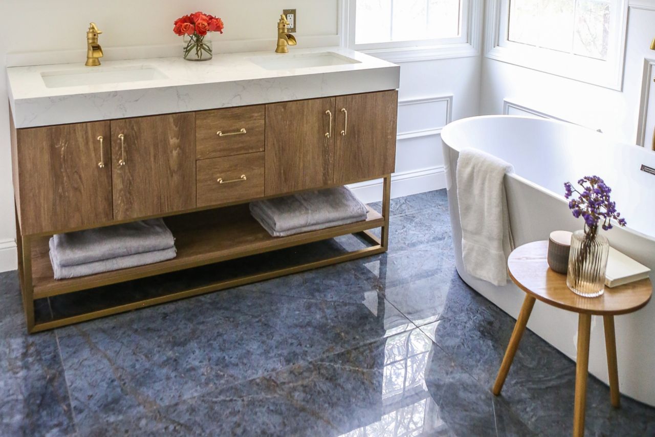 Bathroom with large-format blue marble-look tile floor and white tub.