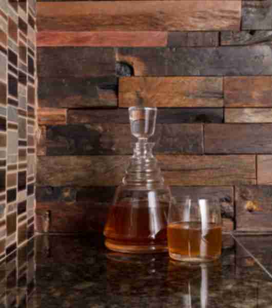 Wet bar with reclaimed wood tile on one wall and a granite mosaic on anther wall. Green granite top.