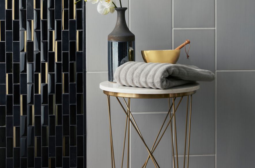 Contemporary shower wall with grey large-format tile and black and gold glass mosaic.