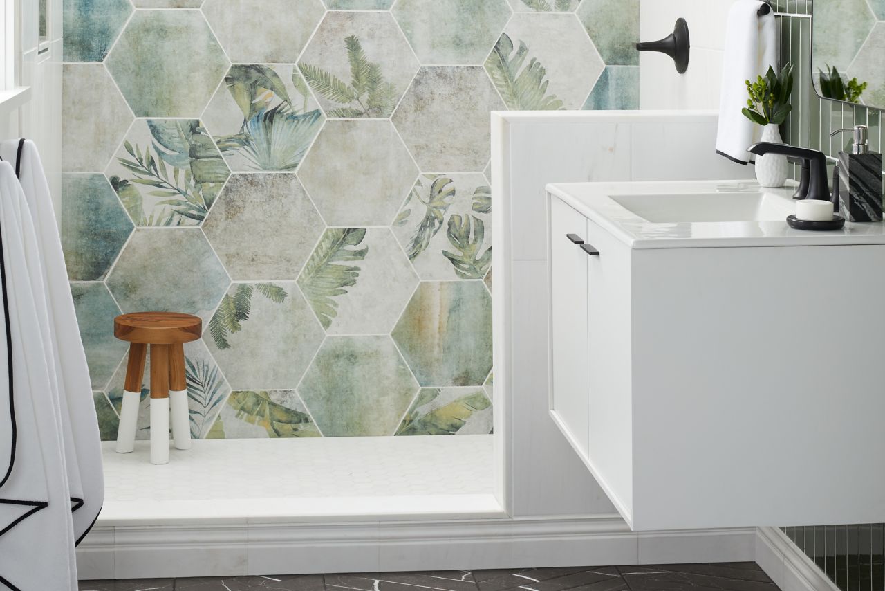 Bathroom with wall in shower with a combination of white marble, patterned porcelain, Black stone porcelain chevron, and glass and marble profiles.