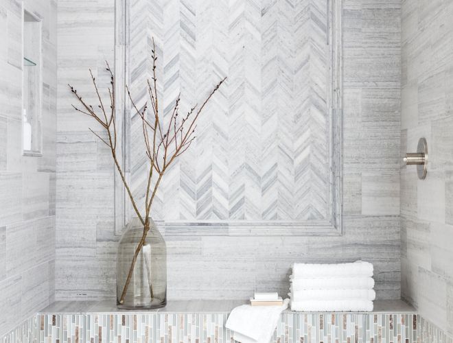 Sophisticated shower with grey limestone in chevron pattern with glass mosaic accents.