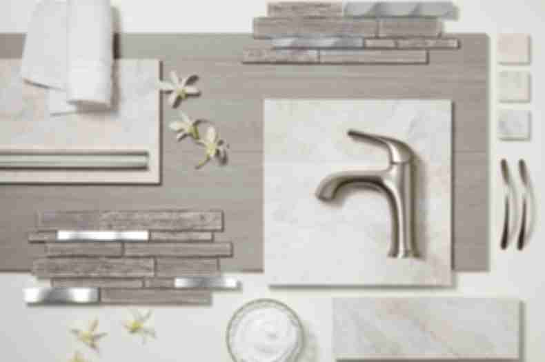 Glass and metal mosaics, grey faux wood tile, white marble tile, and trim pieces lay on a table top with a soft towel, face cream, and flowers.