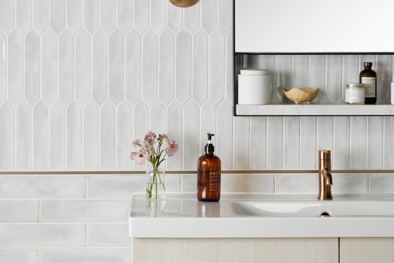 Bathroom sink with a white picket tile wall half wall with green pencil trim and a lower half wall of white subway tile.