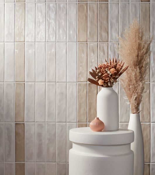 White and cream handmade-look subway tile wall with white table and plants.