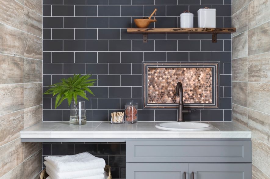 Modern farmhouse style laundry room with blue subway tile and wood-look tile on the walls and encaustic-look tile on the floor.