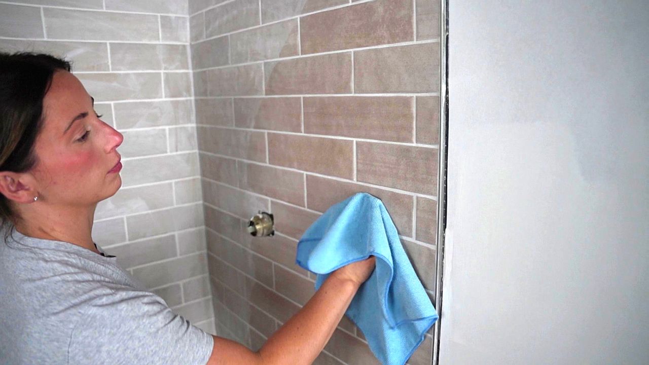 A tile pro uses a microfiber rag to do a final, thorough cleaning of any film present on the surface of tiles before applying grout.