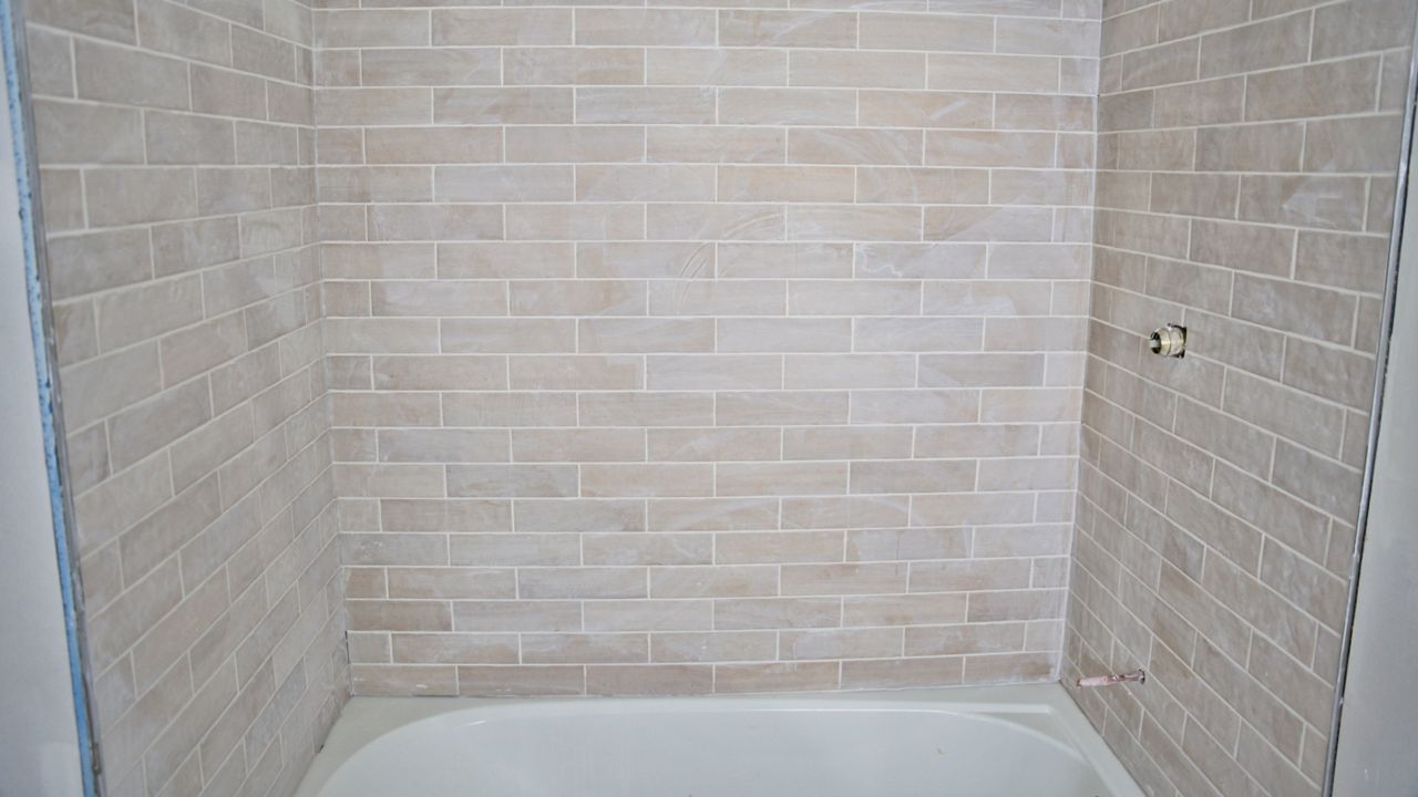 After the initial cleaning, a layer of grout haze remains on this newly tiled shower wall.
