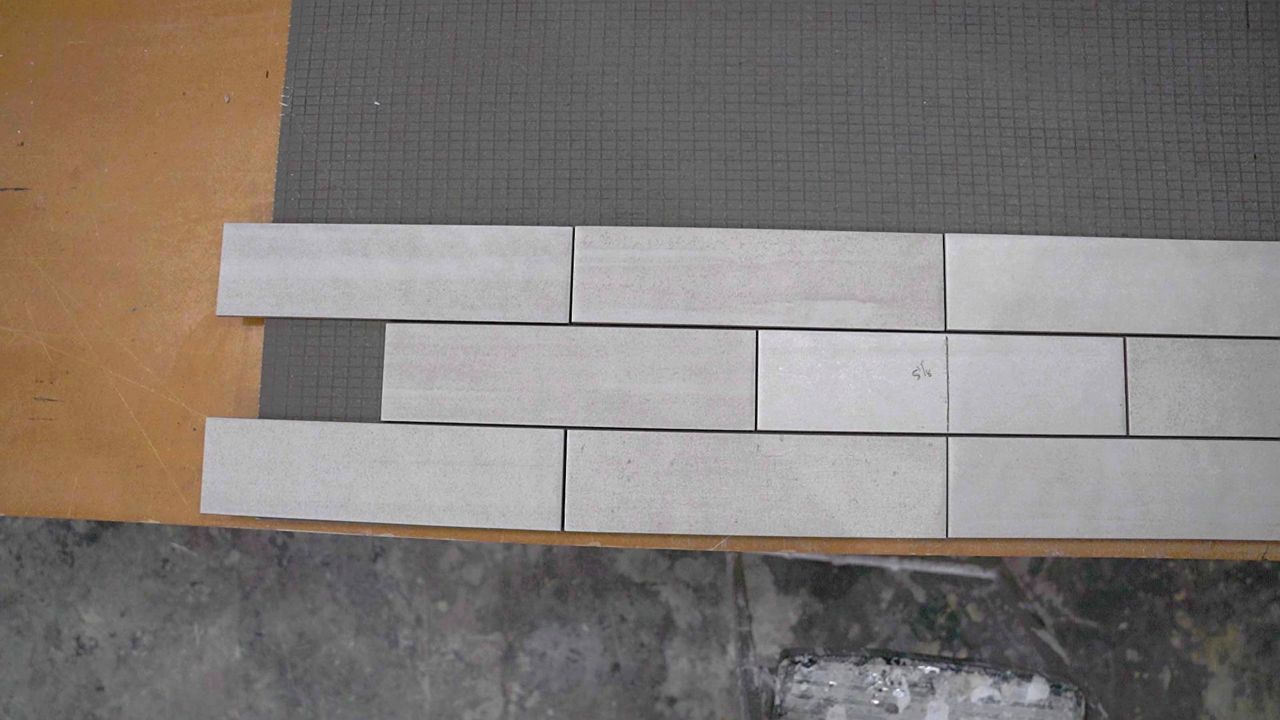 Checking the alignment and placement of shower wall tiles across multiple rows of an offset pattern.