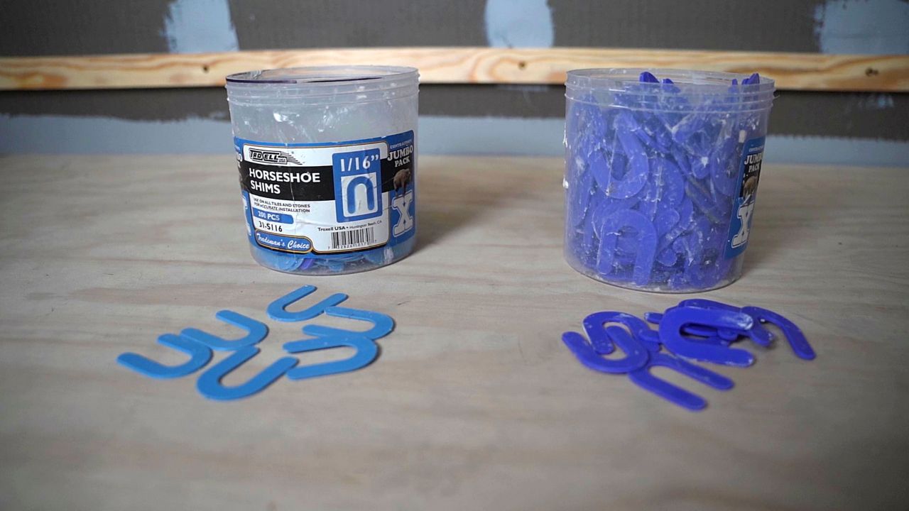 An assortment of blue U-shaped tile spacers, also called horseshoe shims, that will be used for a shower tile installation.