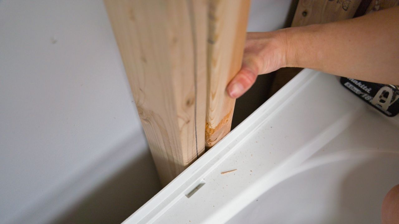 Adjusting the placement of shower wall studs so that they are in alignment and touching the top of the tub flange above a bathtub.