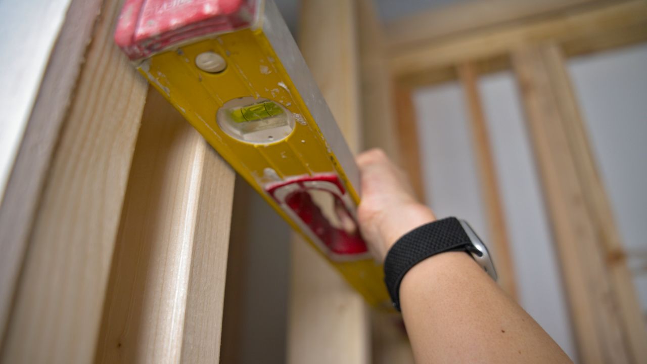 Using a level to check all the studs in a shower wall before tiling.