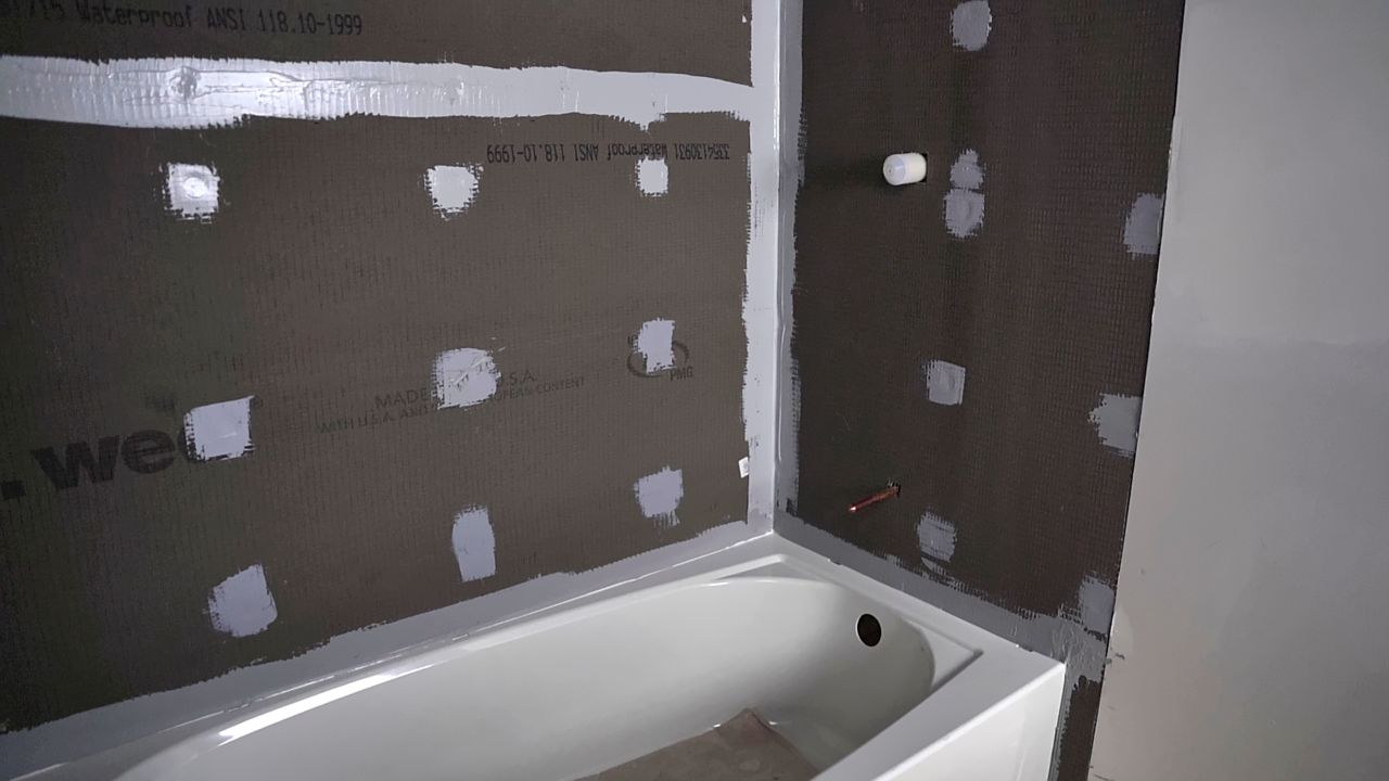 Image showing shower walls above a bathtub that are completely waterproofed and ready for the next steps of a shower tile installation.