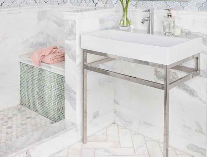 White marble bathroom with arabesque mosaic on walls and herringbone pattern on floor. 