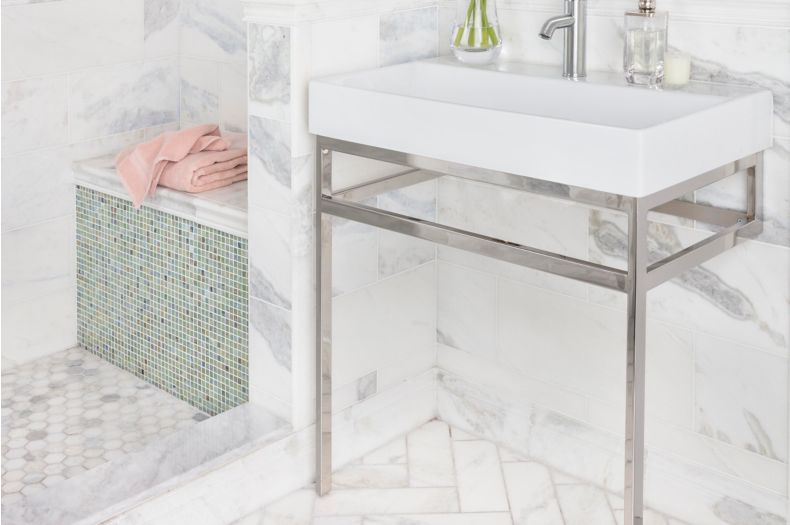 White marble bathroom with arabesque mosaic on walls and herringbone pattern on floor. 