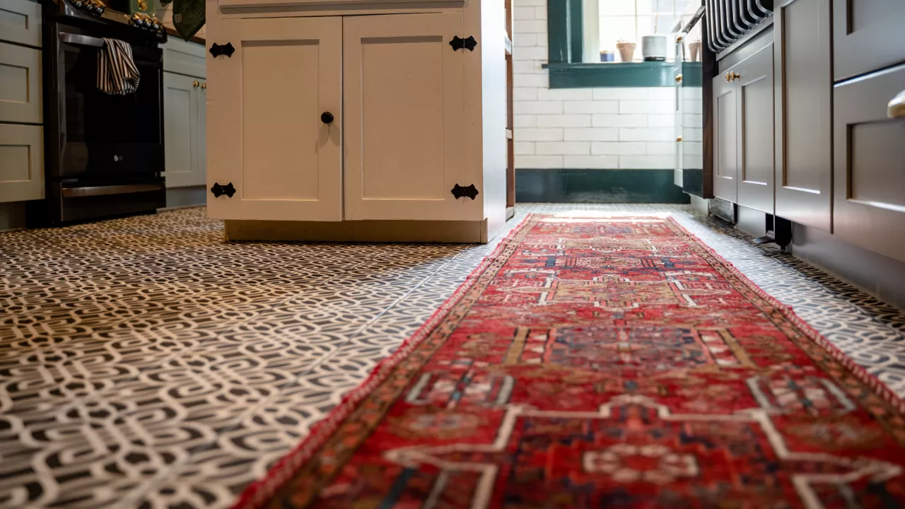  A red Persian runner rug lies on a black and white patterned tile floor in a modern kitchen with gray and white cabinets.